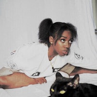 a woman laying on a bed next to a black cat