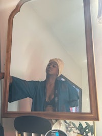 a woman in a blue robe standing in front of a mirror