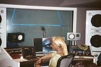 a woman sitting at a desk in a recording studio