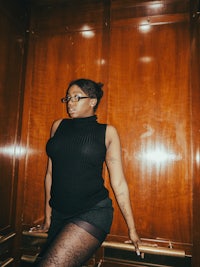 a woman in a black tank top posing in front of a wooden door