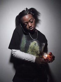 a woman holding a lit cigarette in front of a dark background