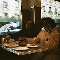 two people sitting at a table eating food