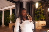 a young woman drinking a glass of wine at a restaurant