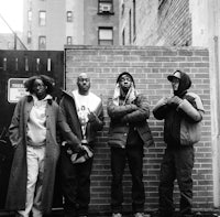 a group of people standing in front of a brick wall